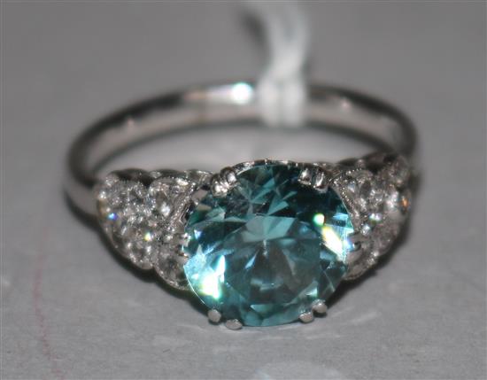 A 9ct white gold, single stone blue zircon dress ring, with diamond cluster set shoulders, size Q.